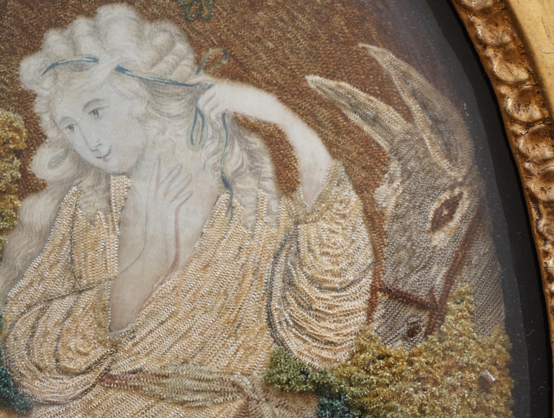 A pair of unusual early 19th century oval silk Chenille embroideries, one depicting a seated lady surrounded by a lion and donkey, the other depicting a seated shepherdess under tree with two sheep. Both have water colou